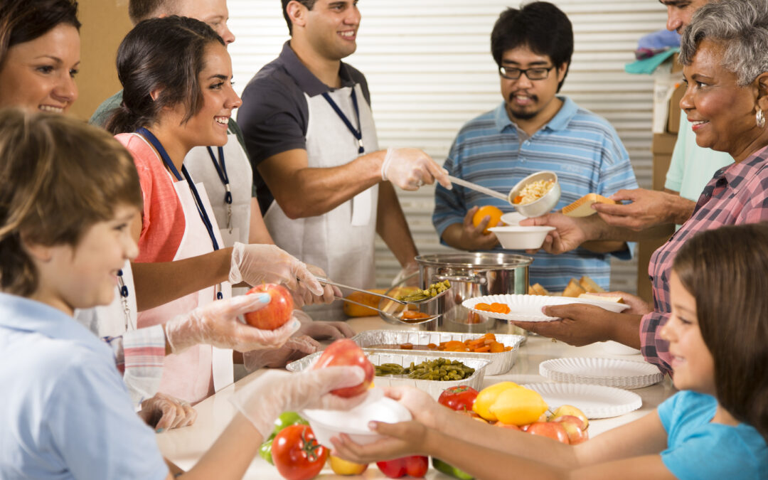 Group of volunteers serve food at community soup kitchen. Charity.